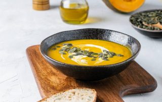 Pumpkin squash soup with seeds, olive oil on light background, thanksgiving food